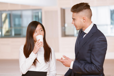 Idea. Young businessman having a cheerful talk sharing his ideas to businesswoman drinking coffee during the coffee break at the meetingの写真素材