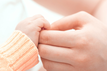 Gentle touch. Mother holding gently the hand of her baby