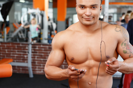 Music helps. Sportive handsome young man listening music in sport gymの写真素材