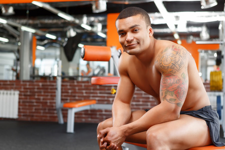 Hand in hand. Muscular man sitting in sport gym and holding hand in hand.の写真素材
