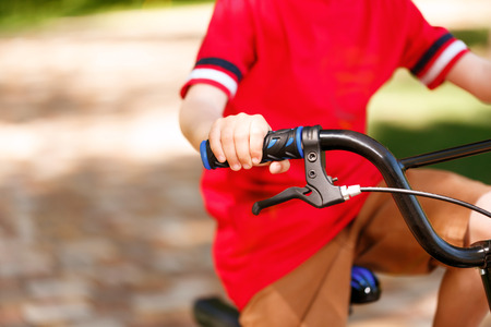 Get to learn. Close up portrait of riding bike little child wearing bright red t-shirt.の写真素材