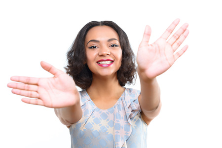 Let me hug you. Pleasant smiling mulatto girl with opened hands showing welcoming embrace on isolated white backgroundの写真素材