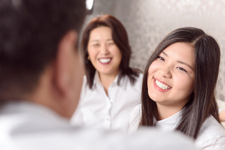 Close relations. Asian family sitting on sofa and chatting at homeの写真素材