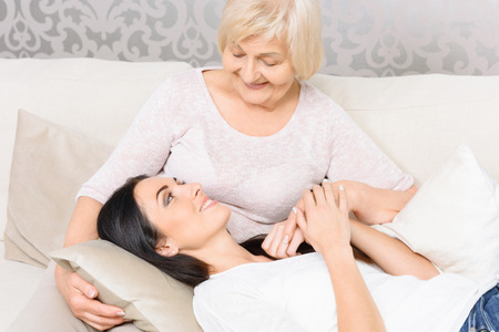 Loving care. Portrait of beautiful young woman lying on knees of her old grandmother.の写真素材
