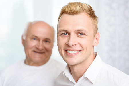 Different generations. Smiling grandson standing on background of his grandpa.