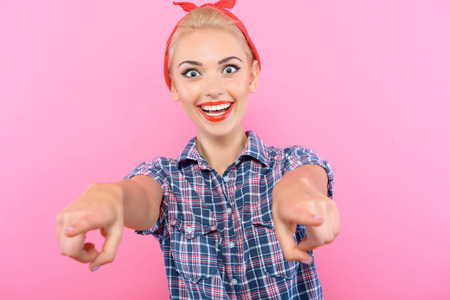 Portrait of a beautiful blond pin up girl with ponytail and red bandana wearing a blue checkered...