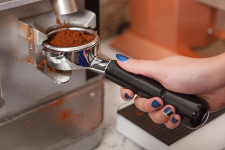 Making fresh. Close-up portrait of female barista preparing freshly made coffee.の写真素材