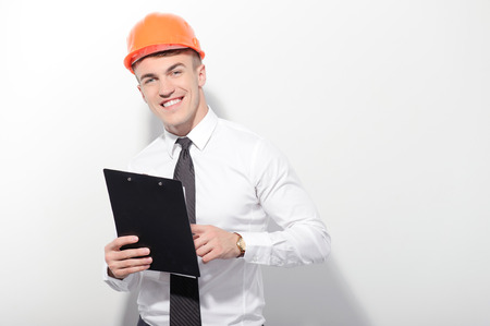 At work. Portrait of attractive foreman standing on white isolated background and holding folder in his hands.の写真素材