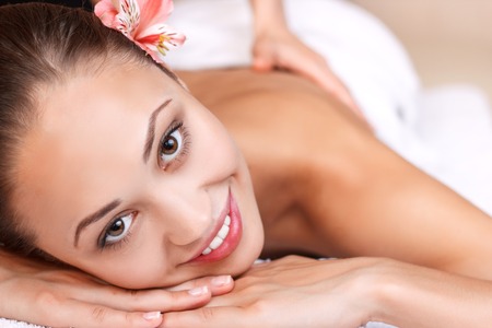 Balance in mind. Close up of cheerful young woman smiling and having massage while lying in spa salon.の写真素材