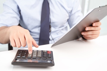 Make real calculation. Close up of true call center operator sitting at the table and holding papers...
