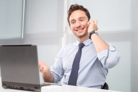 Positivity of moment. Nice smiling call center operator sitting at the table and talking on mobile...