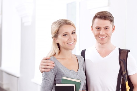 Full of eagerness to study.  Pleasant delighted students holding books and  bonding to each other while expressing joyの写真素材