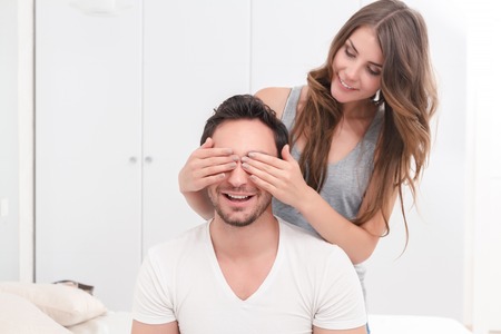 Guess who. Attractive nice young girlfriend closing eyes of her boyfriend and smiling while having great time together.の写真素材