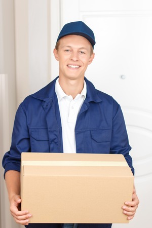 Best service. Positive upbeat deliverymen waiting near the door and holding box while delivering itの写真素材