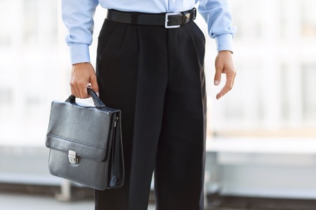 Ready to work. Nice businessman holding case and standing near office buildingの写真素材