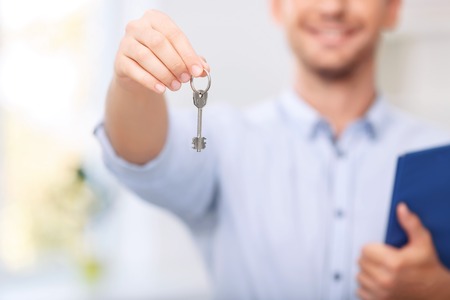 Love my job. Close up of key from new flat in hands of professional realtor doing his jobの写真素材