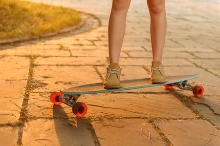 Catch the wind. Close up of young active girl riding on the skateboard while spending free time outsideの写真素材