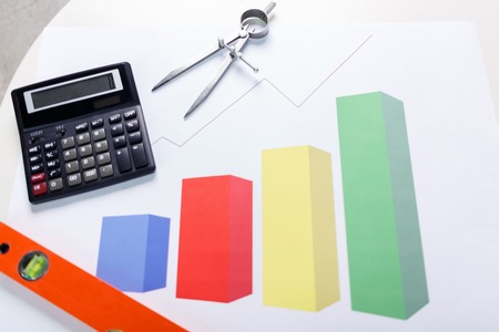 Interesting profession. Top view of calculator and diagram lying on the tableの写真素材