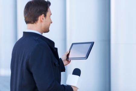 Absorbing info. Young reporter is strongly absorbed by the data he has found on his electronic portable tablet.の写真素材