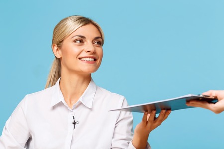 Full of energy. Pleasant cheerful charming TV announcer getting folder and looking aside while preparing to workの写真素材