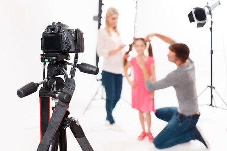 Camera is supported. Photographer leaves his camera fixed safely while helping to prepare little girl for shootingの写真素材