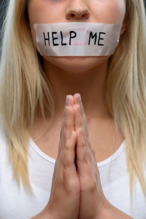 One hope for survival. Close up of beaten young girl holding hands together and begging for helpの写真素材