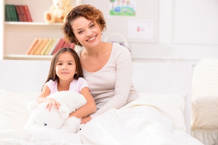 Love you so much.  Peasant cheerful mother and daughter lying on bed and resting together while evincing joyの写真素材