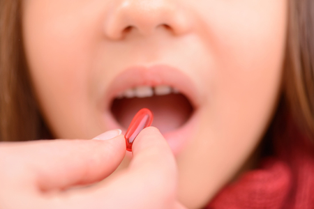 Best remedy. Close up of pill in hands of caring mother holding it and giving medicines to her ill...