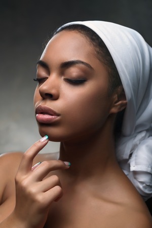 Moment of delight. Portrait of attractive nice young girl holding her hand on face and closing her eyes while feeling contentの写真素材