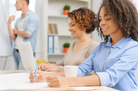 Three pleasant young people are absorbed in completing their tasks on common project.の写真素材
