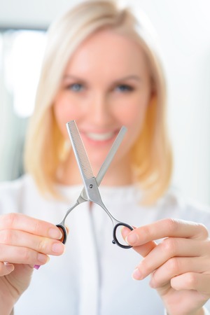 These are scissors. Attractive female hair stylist is showing her scissors for cutting hair.の写真素材