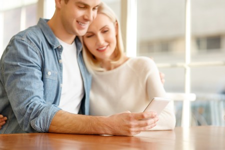 Happy to be together. Pleasant smiling upbeat couple sitting in the cafe and bonding to each other while going to make a callの写真素材