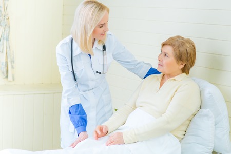 How  do you feel. Pleasant professional nurse talking with her patient and feeling happy while taking care of herの写真素材