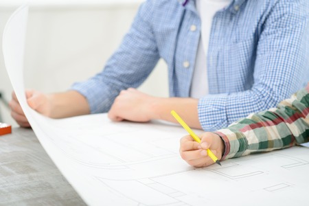 My dream house. Close up of pencil in hands of pleasant little boy holding it and making drawing...