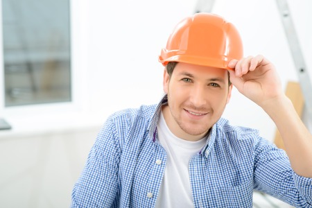 Relax a bit. Pleasant delighted handsome keeping his helmet and smiling while doing renovation