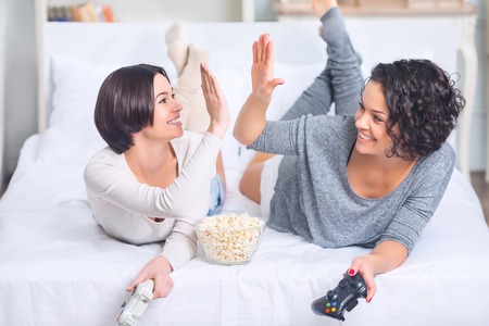 Great game. Two sisters are cheering and high fiving after successful game.の写真素材