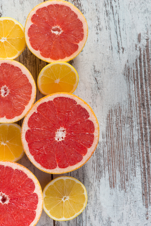 Fresh and healthy. Top view of cut grapefruits and lemons lying on the wooden tableの写真素材