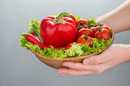 Have a healthy meal. Close up of bowl of fresh vegetables in hands of a person holding itの写真素材