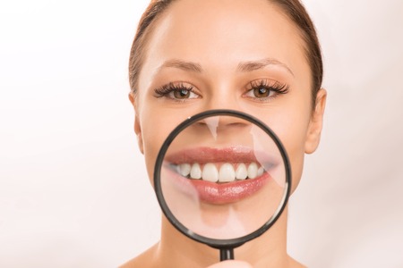 Having fun. Young attractive smiling girl is holding magnifying glass at her mouth and looking amusing.の写真素材