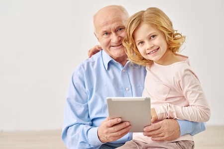 Learning has never been so much fun.  Portrait of  little girl and her grandfather using  laptop in studioの写真素材