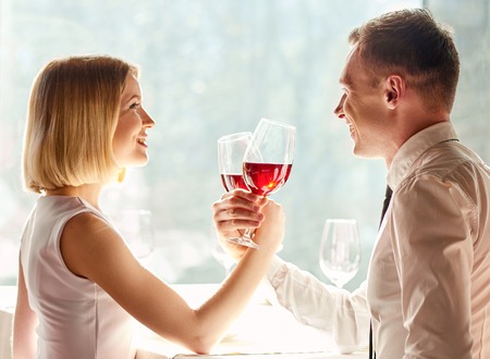 Celebrating their love. Shot of smiling couple holding glassed of wine and happily looking at each other.の写真素材