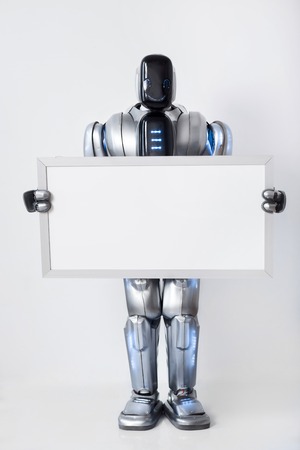 I am real. Delighted smiling modern  smiling robot holding white signboard and  thumbing up while expressing delightの写真素材