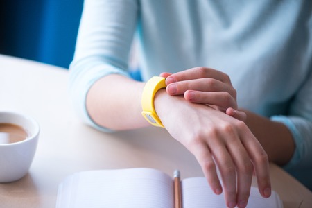 My everyday helper. Close up of tracker on hand of nice woman using it while sitting at the tableの写真素材
