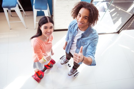 We like it. Cheerful delighted smiling couple thumbing up and showing sign OK while using mini segwayの写真素材