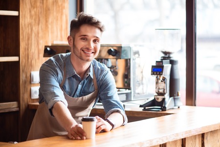Best drinks for you. Pleasant handsome delighted waiter smiling and standing at the counter while...