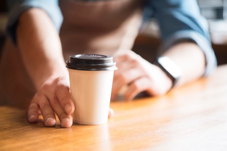 Energy booster. Selective focus of coffee standing on the table while professional waiter holding it and  standing in the backgroundの写真素材