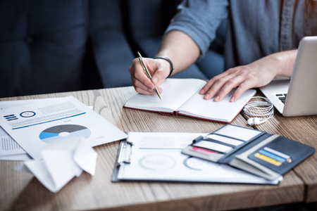 Do it in writing. Pleasant man sitting at the table and making notes while being involved in workの写真素材