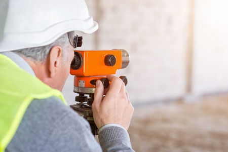 Work up a sweat.  Confident and serious man working with a help of a level standing in a new buildingの写真素材