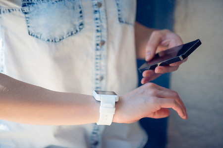 New devices. Modern young woman using her smartphone and her smart watch during her dayの写真素材