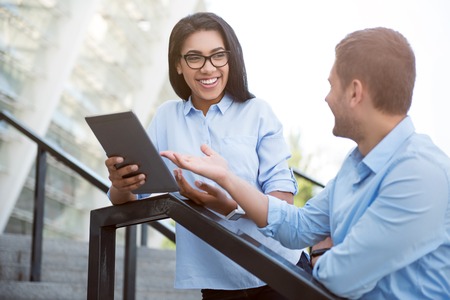 Ready to help you. Positive and smiling young colleagues talking together and discussing something...